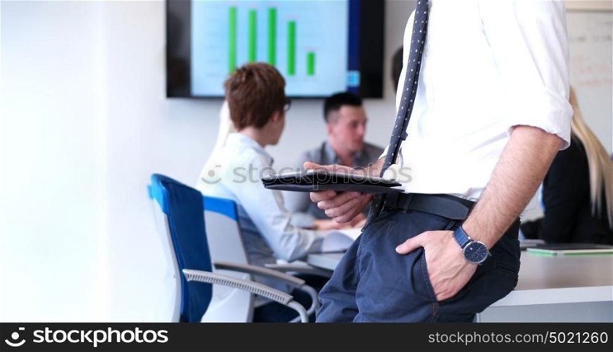 Businessman using tablet computer in office with coworkers in background