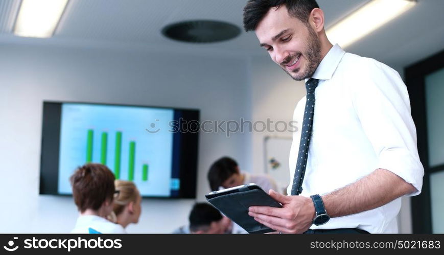 Businessman using tablet computer in office with coworkers in background