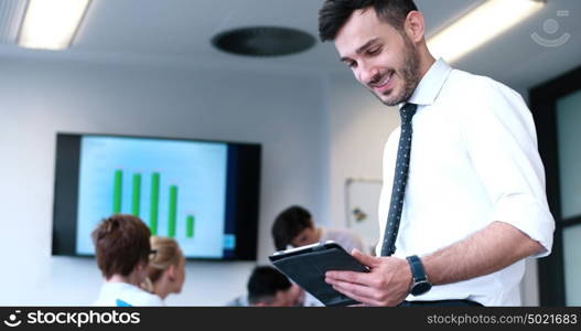 Businessman using tablet computer in office with coworkers in background