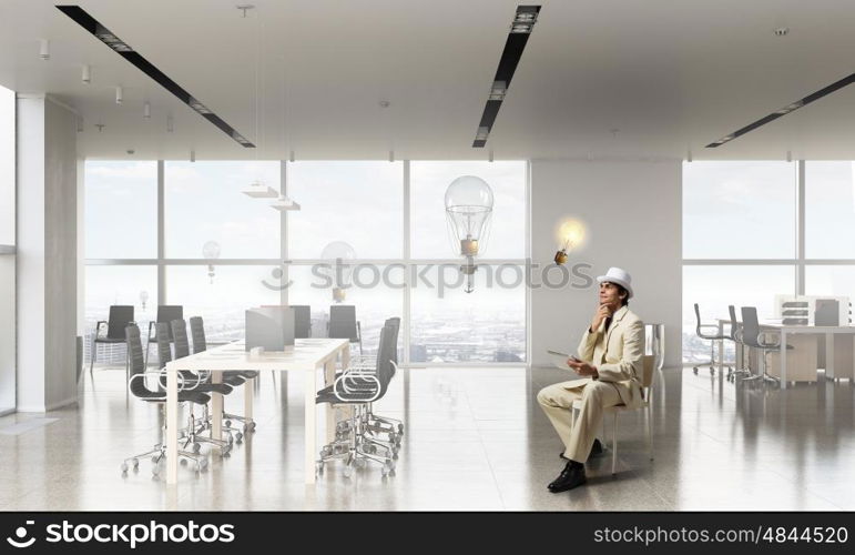 Businessman using tablet device. Elegant businessman in white suit sitting on chair in office interior