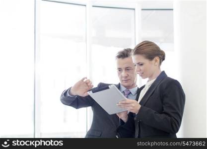Businessman using tablet PC with female colleague in office