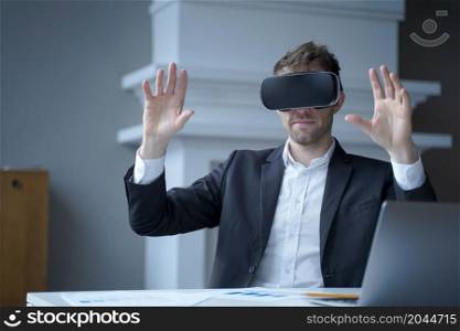 Businessman using technology of augmented reality at home office work. Man CEO in virtual reality glasses with hands up in air. Focused entrepreneur in electronics 3D goggles interacts with simulation. Man CEO in virtual reality glasses with hands up in air at home office interior