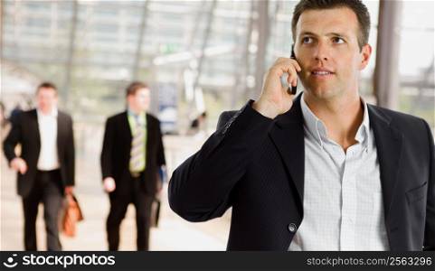 Businessman walking at office lobby talking on mobile phone.