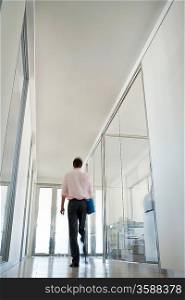 Businessman Walking in Corridor low angle back view.