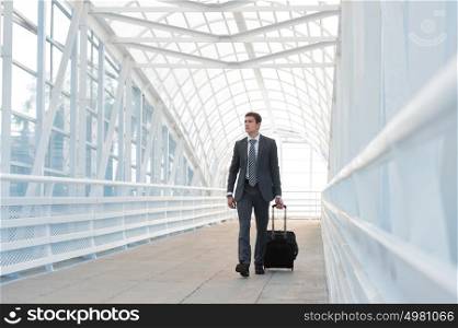 Businessman walking in urban environment of airport with suitcase