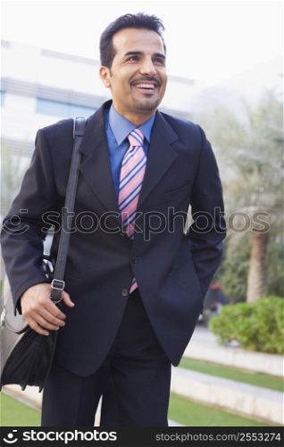 Businessman walking outdoors smiling (high key/selective focus)