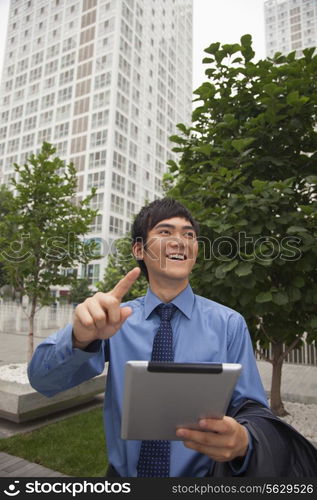 Businessman walking outdoors with his digital tablet