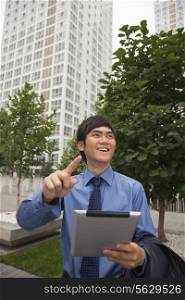 Businessman walking outdoors with his digital tablet