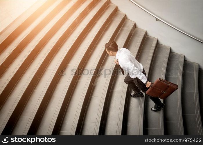 Businessman walking up on stairs and holding briefcase.