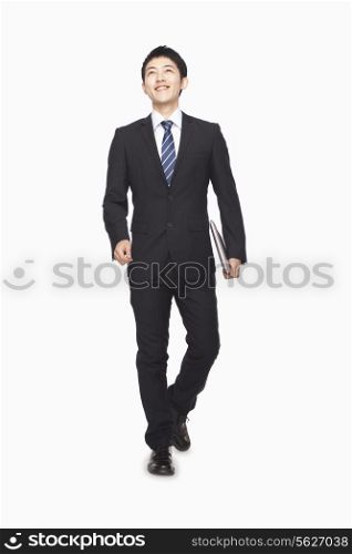 Businessman walking while carrying laptop