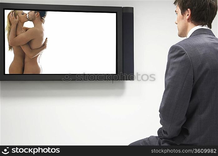 Businessman watching erotic naked couple on flat screen