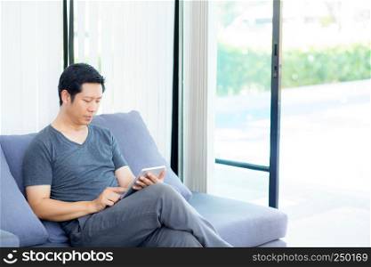 businessman watching media content in a tablet sitting on a sofa at home.
