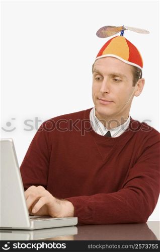 Businessman wearing a propeller beanie and working on a laptop
