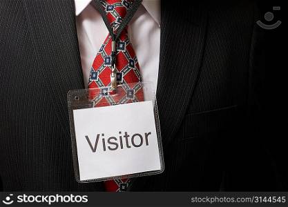 businessman wearing a visitor identification badge around his neck