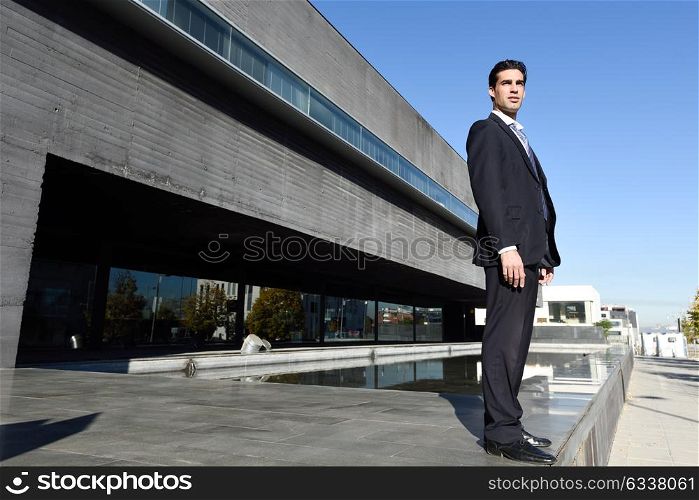 Businessman wearing blue suit and tie in urban background. Man with formal clothes standing outside an office building.