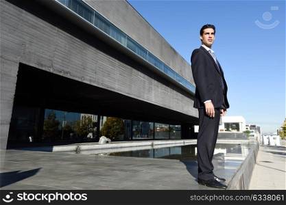 Businessman wearing blue suit and tie in urban background. Man with formal clothes standing outside an office building.