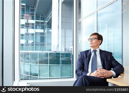 Businessman wearing glasses on the background of a large window in the office