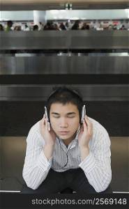 Businessman wearing headphones and listening to music at an airport