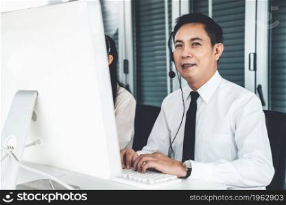 Businessman wearing headset working actively in office . Call center, telemarketing, customer support agent provide service on telephone video conference call.. Businessman wearing headset working actively in office