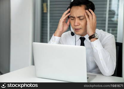 Businessman wearing headset working actively in office . Call center, telemarketing, customer support agent provide service on telephone video conference call.. Businessman wearing headset working actively in office