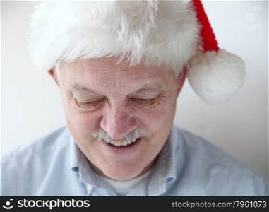 businessman wearing Santa hat looks down and smiles