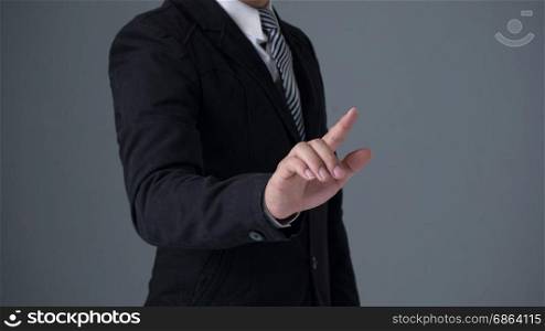 Businessman wearing suite pointing finger . Businessman wearing a black suite pointing finger on gray background