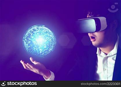 Businessman wearing Virtual reality headset with globe hologram on his hand. Business technology and Metaverse concept