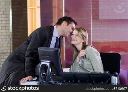 Businessman whispering into a businesswoman&acute;s ear