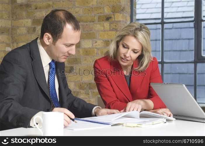 Businessman with a businesswoman looking at documents in an office