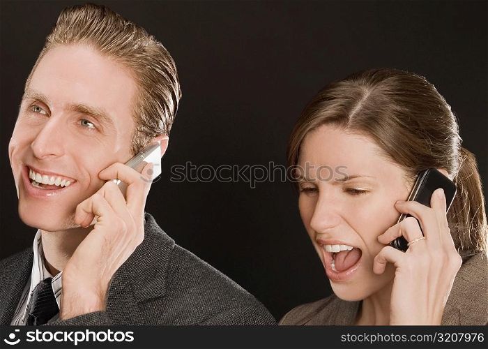 Businessman with a businesswoman talking on mobile phones