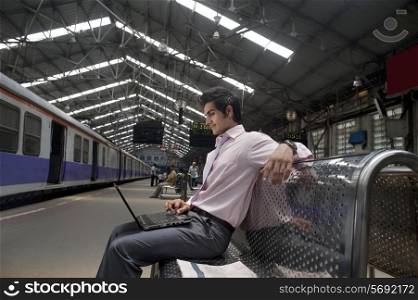 Businessman with a laptop at a train station