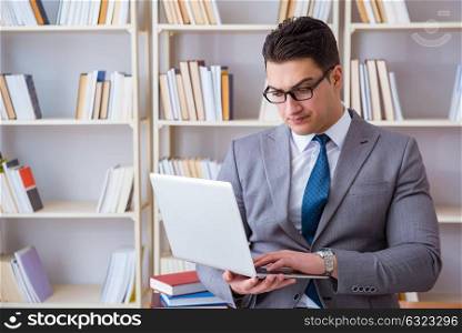 Businessman with a laptop working in the library