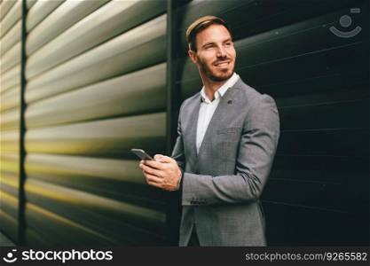 Businessman with a phone by the black wall