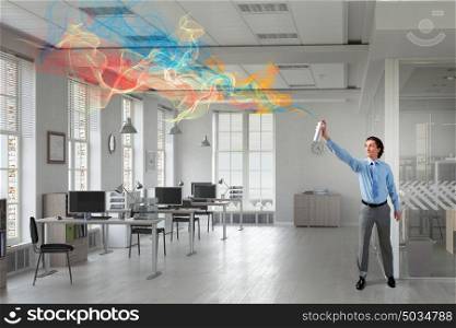 Businessman with aerosol can. Businessman in office interior spraying paint from aerosol