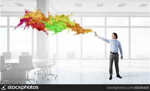 Businessman with aerosol can. Concept of creativity with businessman in office spraying paint from balloon