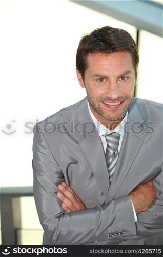 Businessman with arms crossed smiling.