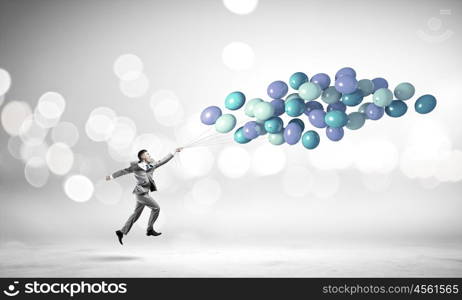 Businessman with balloons. Cheerful businessman running with bunch of colorful balloons