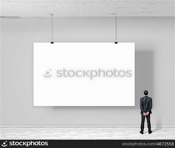 Businessman with banner. Image of businessman standing with back and looking at white banner