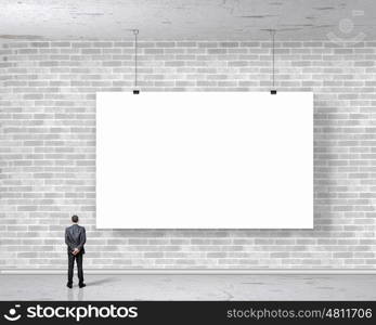 Businessman with banner. Image of businessman standing with back and looking at white banner