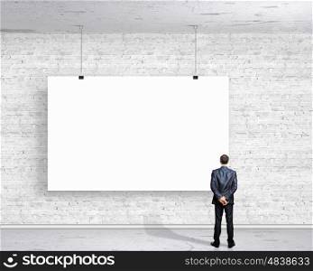 Businessman with banner. Image of businessman standing with back and looking at white banner