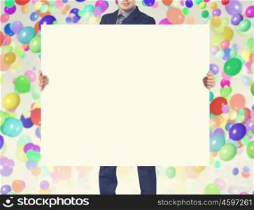 Businessman with banner. Unrecognizable businessman showing white blank banner and colorful balloons at background