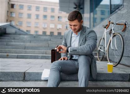 Businessman with bike having lunch at the office building in downtown. Business person riding on eco transport on city street, urban style