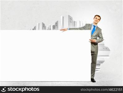 Businessman with blank banner. Businessman with blank banner standing against urban scenic. Place for text