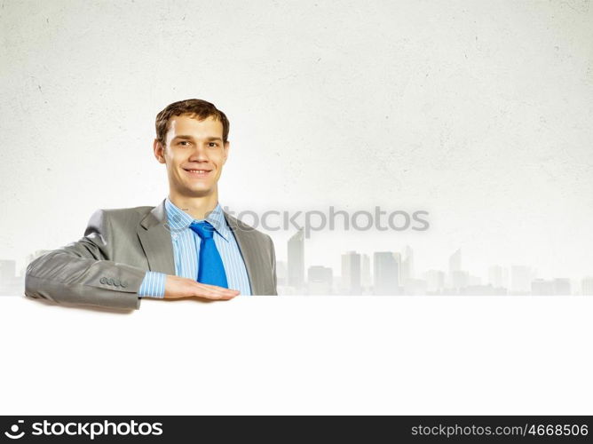 Businessman with blank banner. Businessman with blank banner standing against urban scenic. Place for text