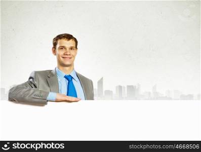 Businessman with blank banner. Businessman with blank banner standing against urban scenic. Place for text
