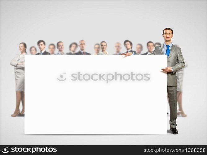 Businessman with blank banner. Image of businessman with blank banner standing against crowd of business people