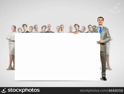 Businessman with blank banner. Image of businessman with blank banner standing against crowd of business people