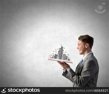 Businessman with book in hands. Businessman holding opened book with construction model on pages