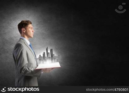 Businessman with book in hands. Businessman holding opened book with construction model on pages