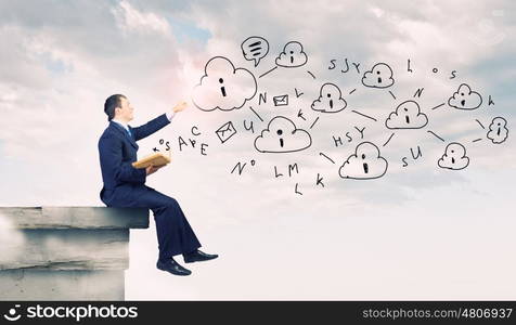 Businessman with book. Young businessman reading book sitting on roof of building